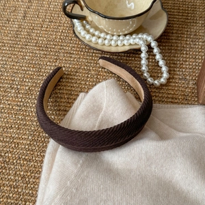 Detail view of dark coffee fabric headband with twill texture on a soft knit background