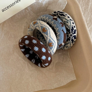 Close-up of four thick knitted elastic hair ties with floral and polka dot patterns