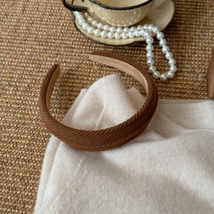 Close-up of brown twill fabric headband with soft lining on a cozy knitted background