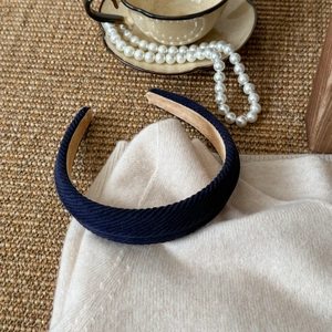 Detail of dark blue twill fabric headband on white knit sweater with vintage decor