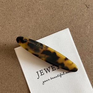 Detailed close-up of handmade tortoiseshell cellulose acetate clip with France lettering