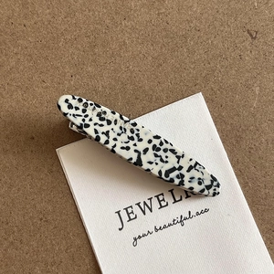 Detailed macro view of black and white spotted acetate hair clip with France handmade engraving