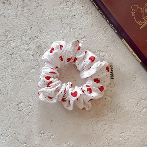 White cotton strawberry print scrunchie with cute woven label on stone background