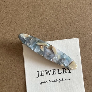 Detail of a vintage rectangular acetate hair clip with blue and grey marble patterns