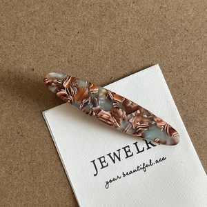 Detail of acetate hair clip with brown marble texture and France Handmade engraving