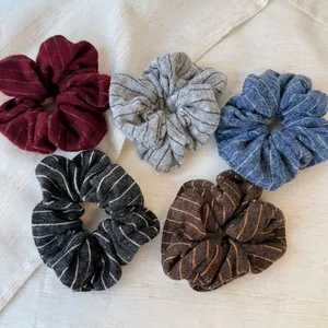 Five-piece set of striped knit scrunchies in retro colors on a soft fabric background