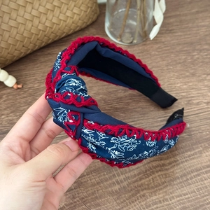 Detail of bohemian floral headband with red crochet edge and twisted knot design