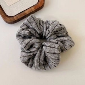 Close-up of a gray striped knit hair scrunchie showing soft fabric texture and pleated detail