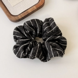 Detailed close-up of dark grey striped knit scrunchie texture and soft plush fabric