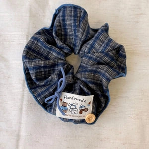 Haargummi mit blau-grauem Karomuster, Handmade-Etikett und dekorativem Holzknopf