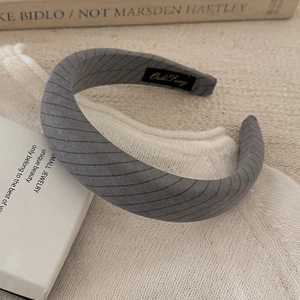 Detail of grey striped wide headband on a white knitted fabric for hair styling