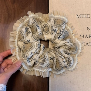 Close-up of bohemian paisley scrunchie with lace edges and elegant white faux pearls