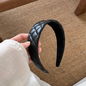 Close-up of black quilted leather headband with classic diamond pattern and wide padded texture