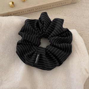 Close-up of a premium black and white striped oversized scrunchie on soft knit texture