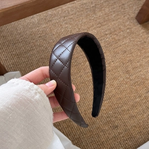 Close-up of quilted coffee leather wide headband showing refined diamond stitching texture