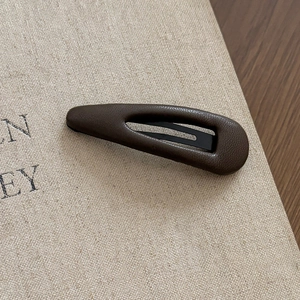 Macro shot of dark brown leather textured triangle hair clip with premium matte finish