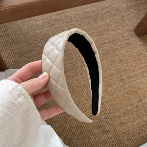 Detail view of beige quilted leather headband featuring classic diamond stitching pattern