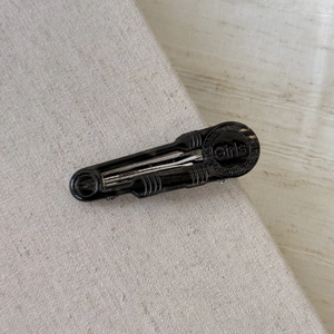 Fermaglio per capelli minimalista in acetato nero con incisione Girls su sfondo di lino beige