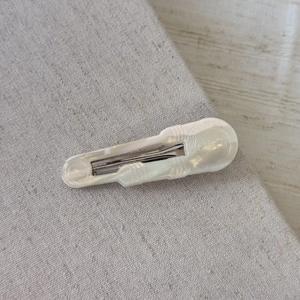 Dettaglio del fermaglio per capelli in acetato bianco perlato con scritta Girls su tessuto