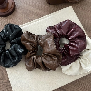 Chouchous en similicuir noir, marron, bordeaux et beige disposés sur un livre
