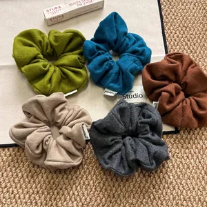 Five-piece set of Morandi colored fabric scrunchies with Happiness labels on a rustic rug