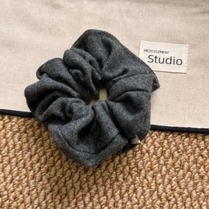 Dark grey fabric scrunchie with thick pleats and elegant textured finish for women