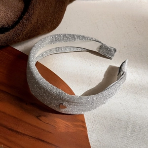 Detail shot of a grey polka dot headband with a small silver heart metal charm attachment