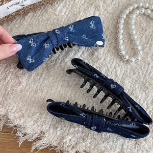 Denim bow banana hair clips in light and dark blue with white patterns on a soft background