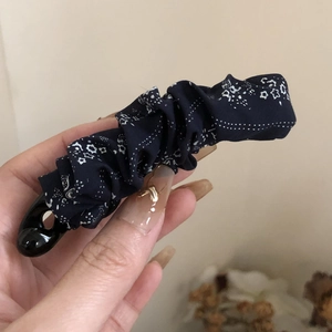 Close-up of pleated navy blue fabric banana hair clip with white star patterns
