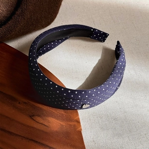 Close-up of navy polka dot headband featuring textured fabric and silver heart detail
