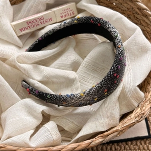 Detail of tweed headband with colorful pom poms and non-slip lining in a basket