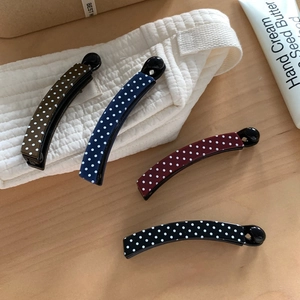 Polka dot banana hair clips in four colors on a wooden table for chic ponytail styles