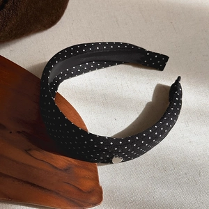Detail shot of black polka dot headband with a small silver heart charm and non-slip lining