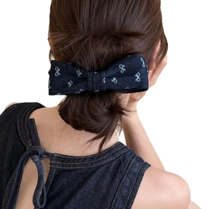 Blue denim bow hair clip with vintage patterns shown on a low bun hairstyle