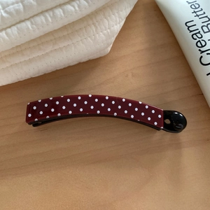 Burgundy red polka dot banana hair clip for elegant high ponytail styling on wood surface