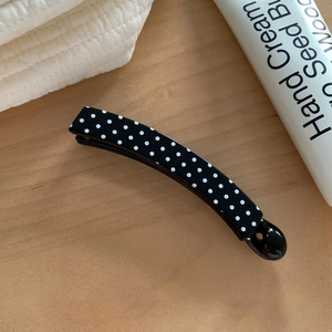 Close-up of a glossy black banana clip with white polka dots for high ponytails
