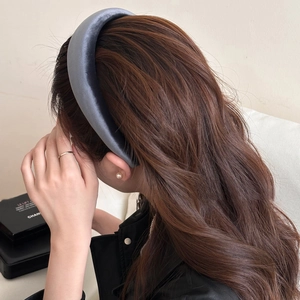 Macro side view of a thick grey-blue satin sponge headband with elegant silky texture