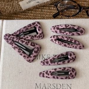 Vintage pink leopard print hair clips set with fabric texture on flat lay background