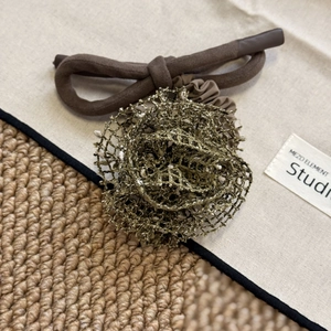 Détail d'un chouchou rose tricotée vert olive avec des détails de corde rustique marron