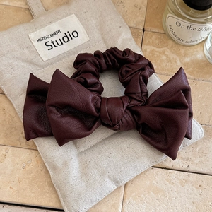 Faux leather wine red bow scrunchie with pleated design on beige linen fabric