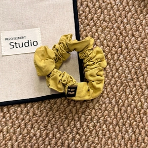 Detail of yellow polka dot scrunchie fabric and black handmade label on woven mat