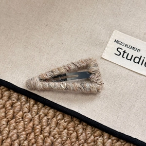 Macro shot of knitted wool triangular hair clip featuring mixed beige and brown yarn texture