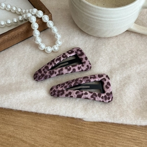 Detail of pink leopard print triangle hair clips on soft knit fabric with pearls