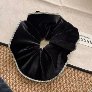 Detail of premium black velvet scrunchie with sparkling crystal rim and soft texture