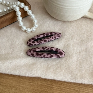 Close-up of pink leopard print BB hair clips with fabric texture on a soft background