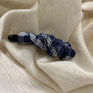 Close-up of blue and white checkered fabric texture on a pleated banana hair clip