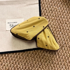 Close-up of yellow polka dot fabric scrunchie with lace edge and brown trimming details