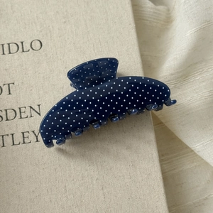 Detail of navy blue polka dot acetate hair claw clip showing polished finish and teeth