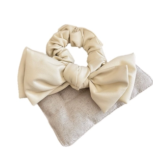 Elegant cream PU leather scrunchie with a large bow design and textured finish