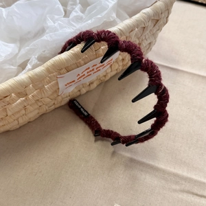 Close-up of wine red knitted headband with teeth detail and Hand Made fabric label